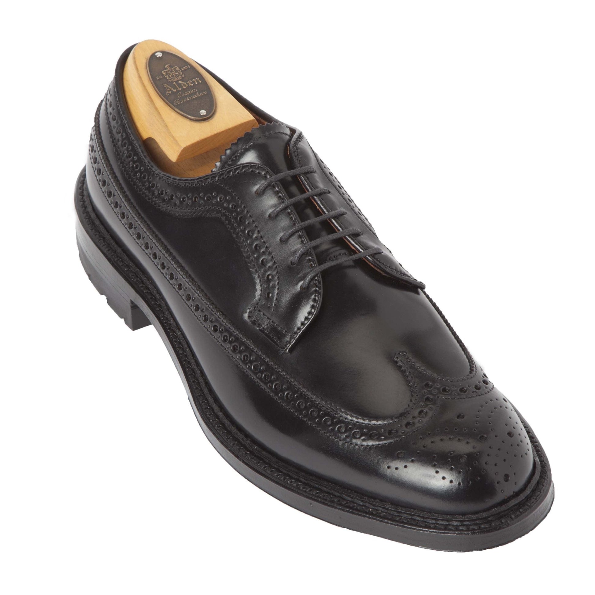 The Alden Madison 9751C Long Wing Blucher is a polished black leather dress shoe with brogue detailing and laces, crafted from luxurious Black Shell Cordovan. It features a wooden shoe tree inside and is completed with a robust Commando Sole for durability.