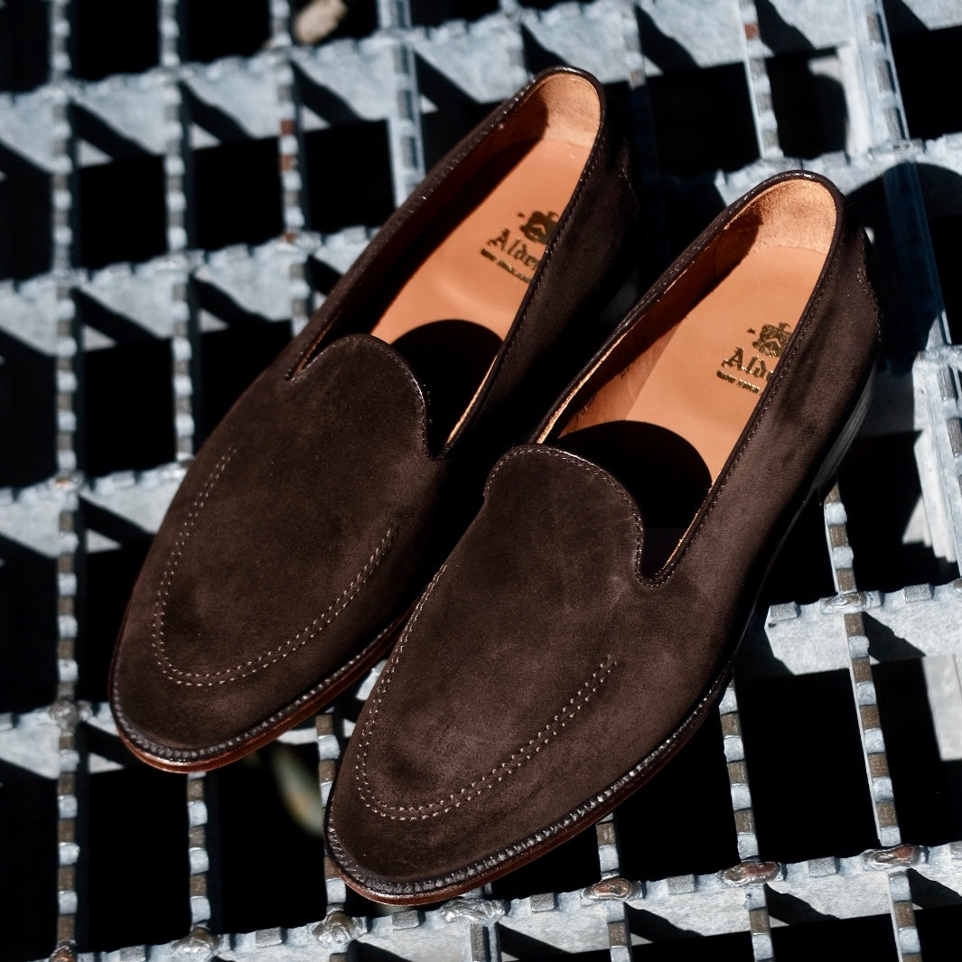 The ALDEN SHOES D5105 - Vanderbilt in Dark Brown Suede, featuring a tan inner lining and Flex Leather Sole, is showcased on a geometric metal grate under sunlight.