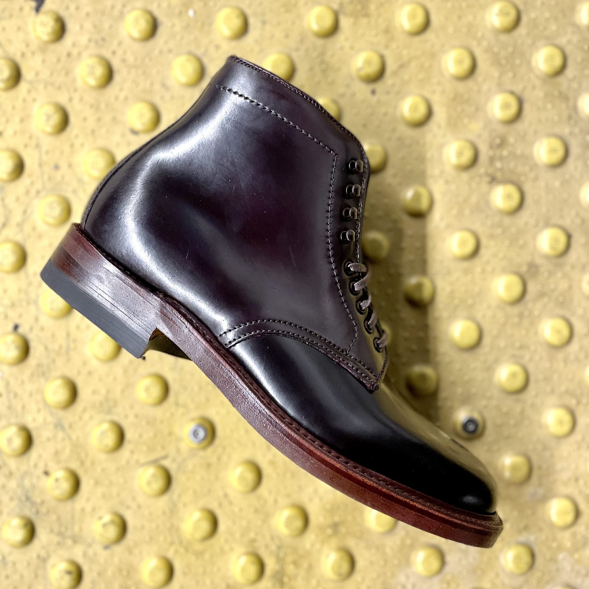 The Alden Madison D1854H - Plain Toe Boot with Neocork Sole in Color 8 Shell is displayed on a yellow textured surface featuring raised circular bumps.