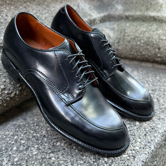 Alden Madison’s N6406 - Black Shell V-Tip on 379X dress shoes with laces, brown inner lining, and sturdy rubber heel are displayed on a gray stone surface.