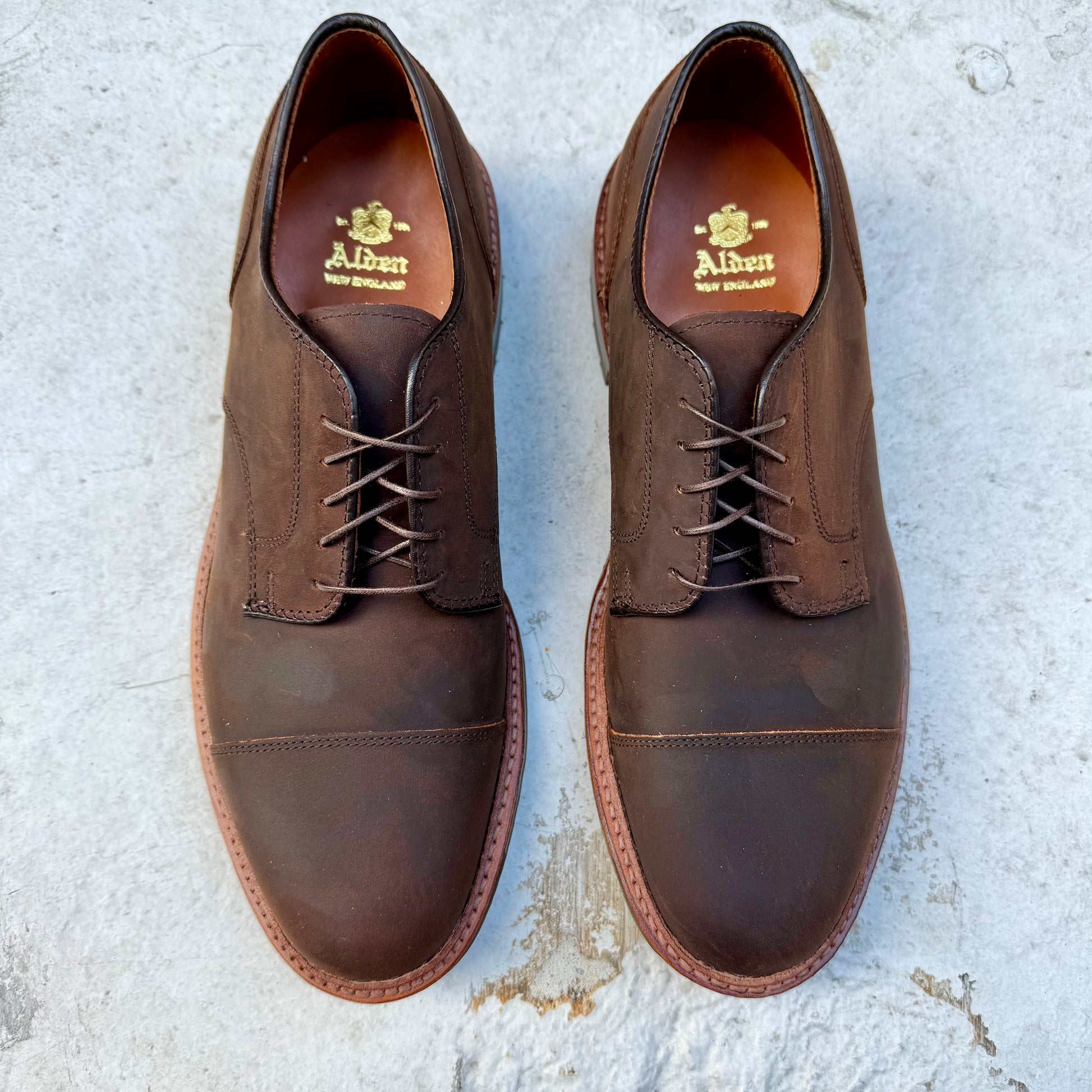 These brown leather Alden Madison D4519C Tobacco Chamois Cap Toe Bluchers, with laces and a polished cap toe design, are set against a light gray background with the brand name inside.