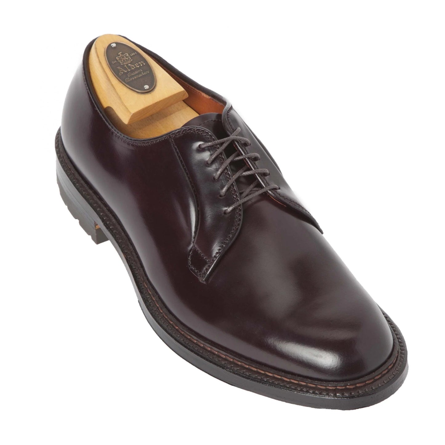 Alden Madison presents the 990C - a polished dark brown leather plain toe blucher with a lace-up design and black rubber Commando Sole. It includes a wooden shoe tree embossed with the Allen Edmonds logo.