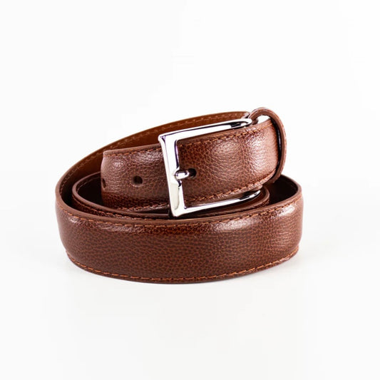 The MB 0341 - Brown Alpine Grain Belt by Alden Madison is coiled on a white background, showcasing its textured design and visible stitching. The shiny silver buckle elegantly complements the sophisticated craftsmanship, proudly Made in USA.