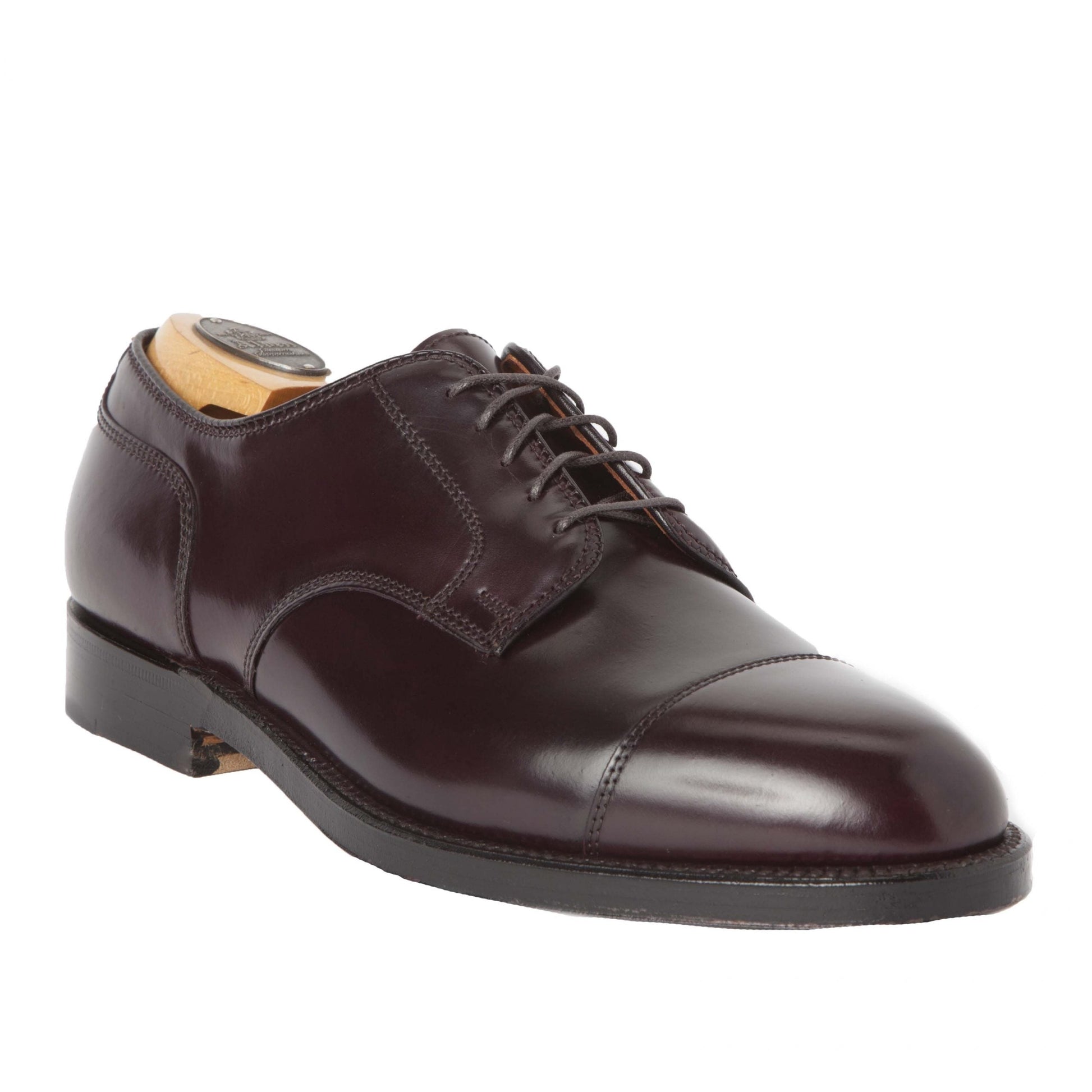 The Alden Madison 2160, a Color 8 Shell Cordovan cap toe blucher, features polished dark brown leather with a black sole. Displayed at an angle, the shoe highlights its laces and wooden shoe tree inside.