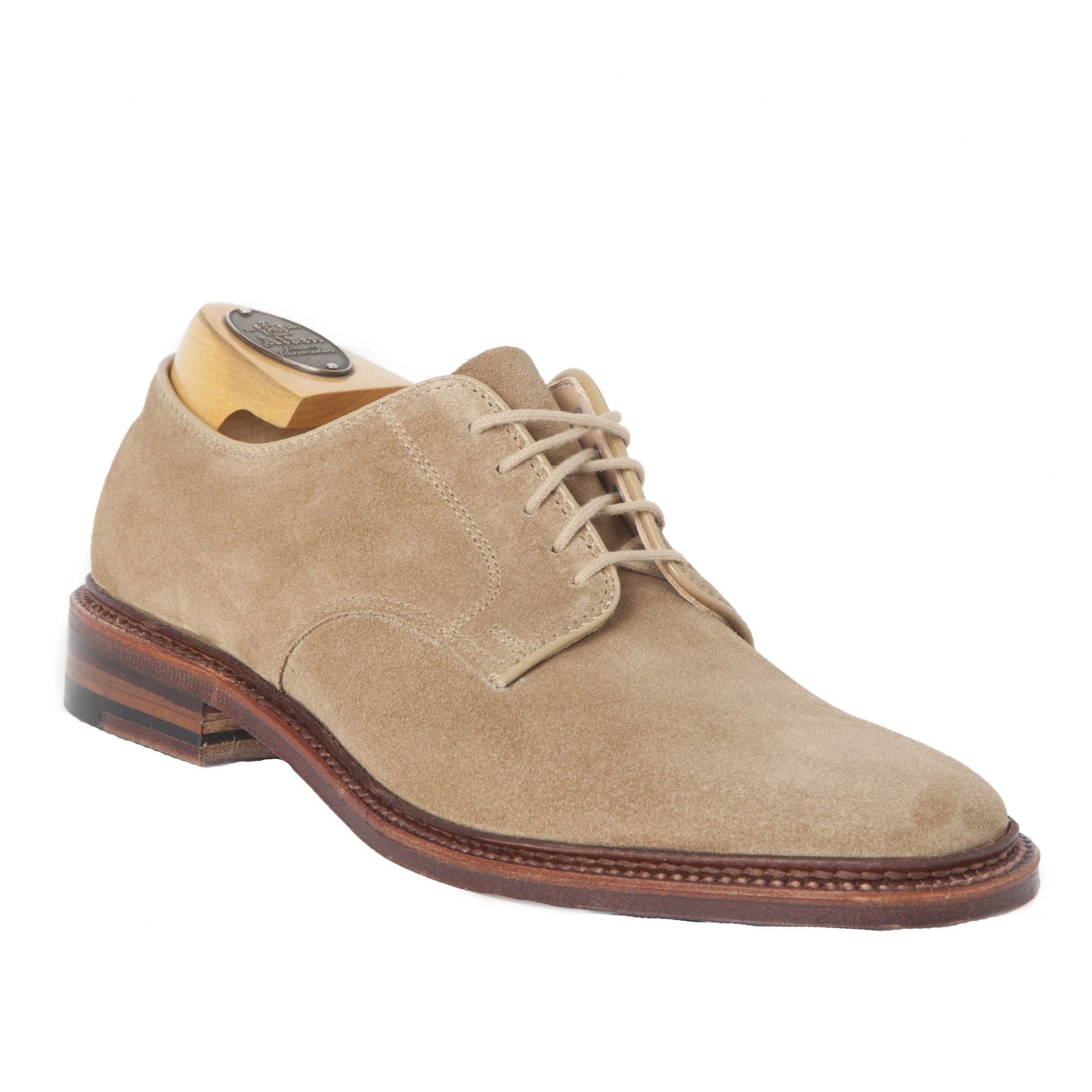 The Alden Madison 29332F Unlined Plain Toe Blucher is a tan suede dress shoe crafted on the Barrie Last. It includes laces, a wooden shoe tree, a Flex Leather Sole with a brown finish, and a dark heel for added elegance.
