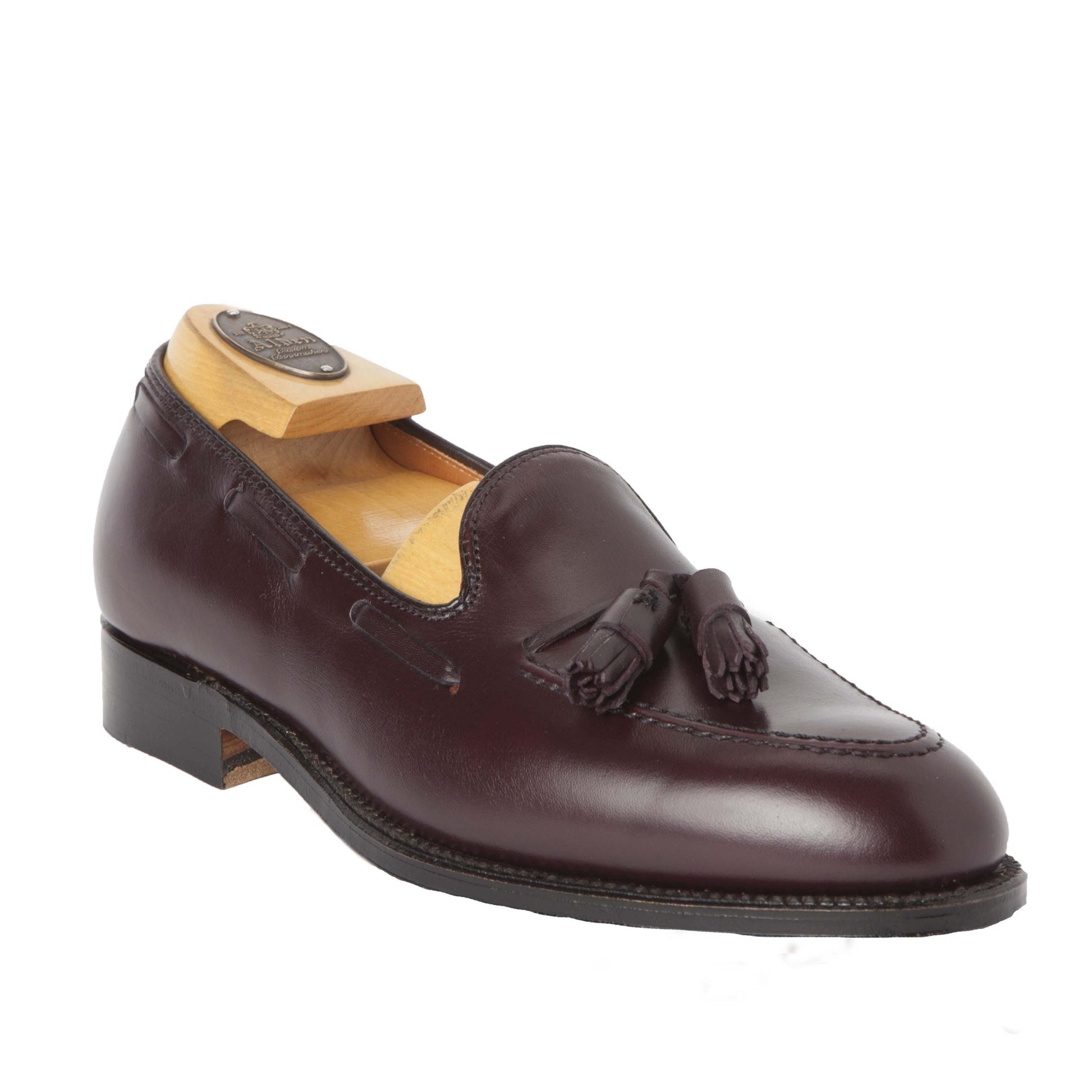 The Alden Madison 663 - Tassel Loafer in Burgundy Calfskin is a polished, dark burgundy shoe with tassels, designed on the Aberdeen Last. It features a low heel, leather sole, and includes a wooden shoe tree, elegantly displayed against a plain white background.