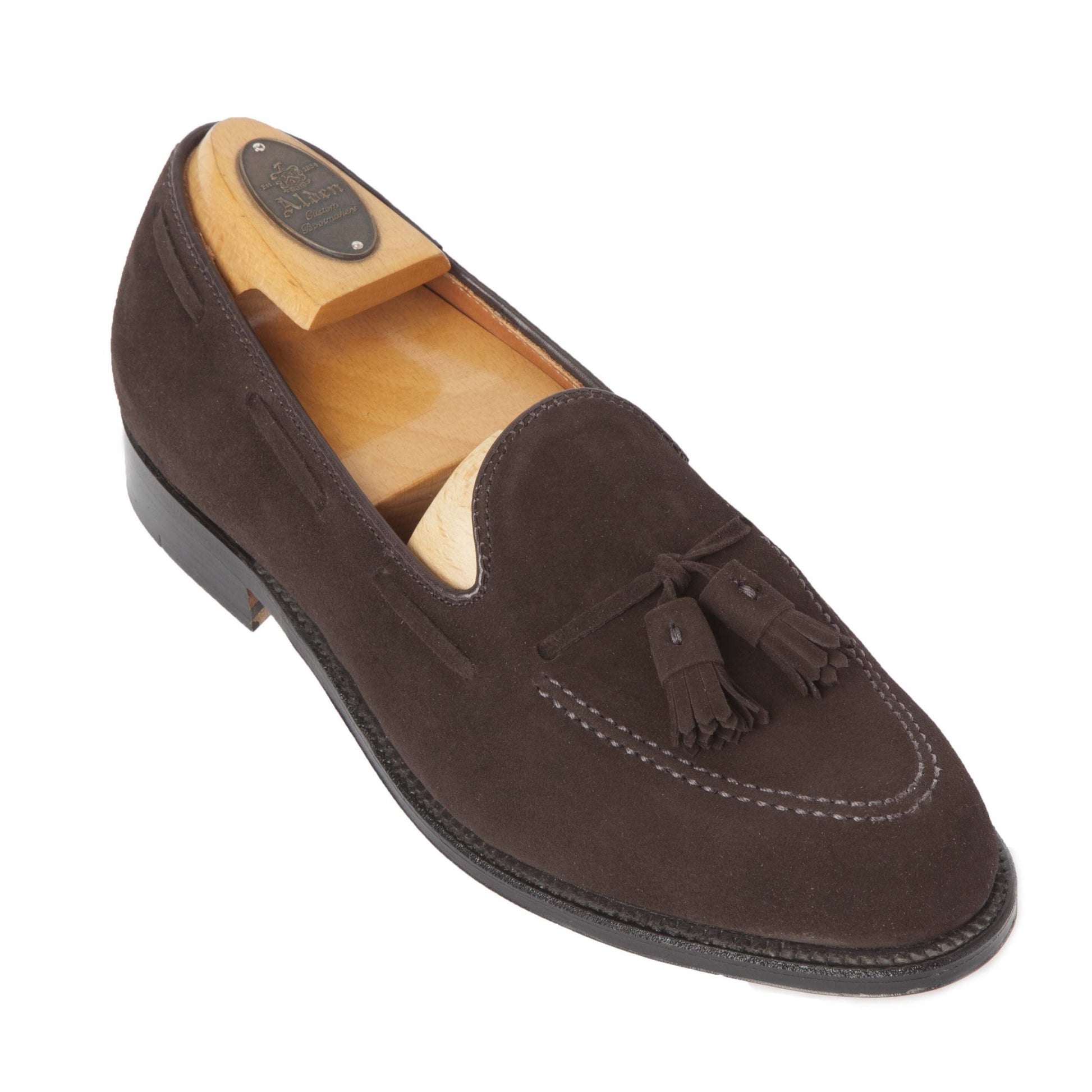 The Alden Madison 666 Tassel Loafer in Brown Suede, crafted on the Aberdeen Last, boasts a sleek design and detailed stitching. Featuring a durable leather sole and including a wooden shoe tree for shape maintenance, the loafer is prominently displayed against a white background.