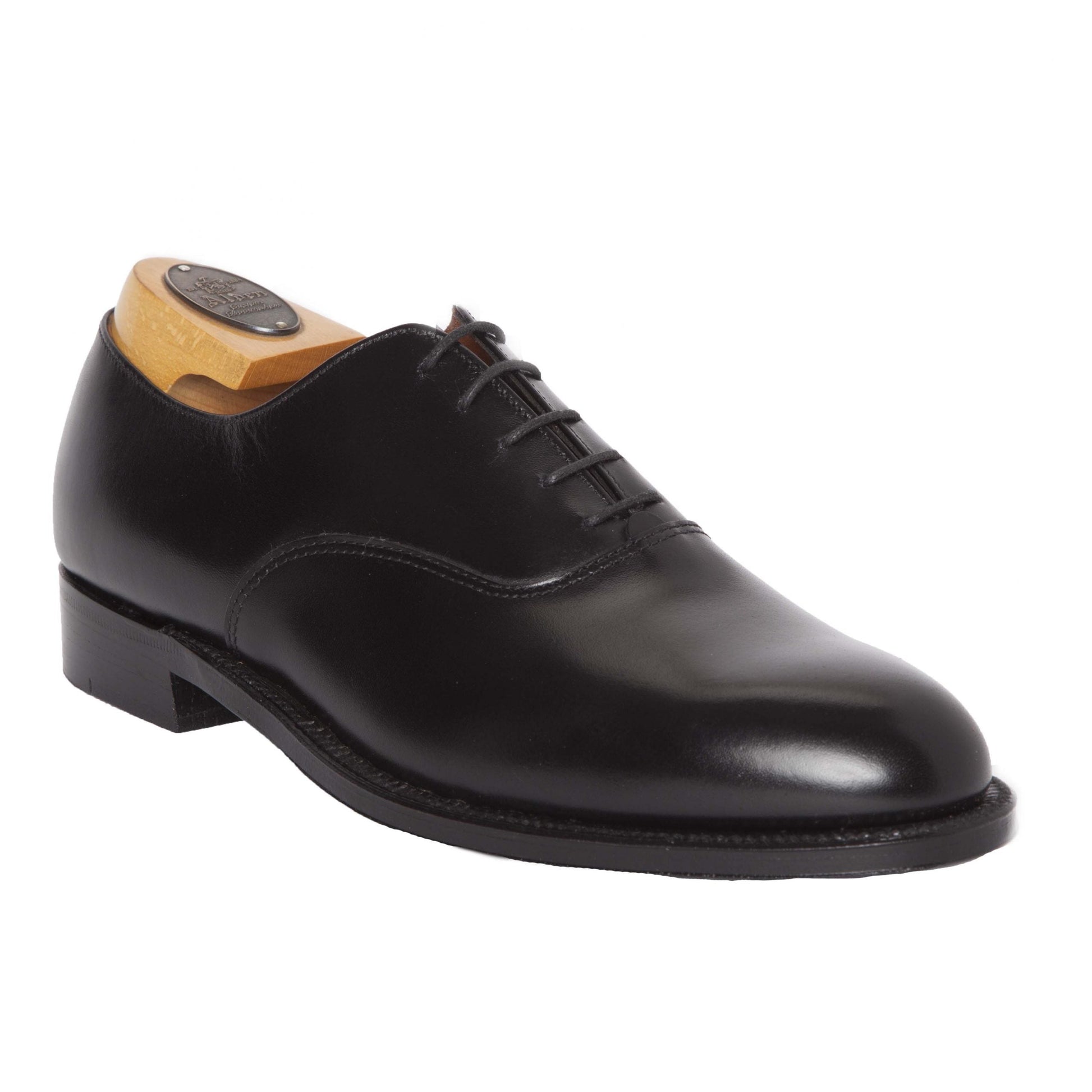 The Alden Madison 932 - Plain Toe Bal in Black Calfskin showcases polished black Oxford elegance, featuring closed lacing with a wooden shoe tree. Designed on the Aberdeen Last with a low heel and Single Oak Leather Sole, the shoe’s sleek silhouette is artfully displayed from side to front.