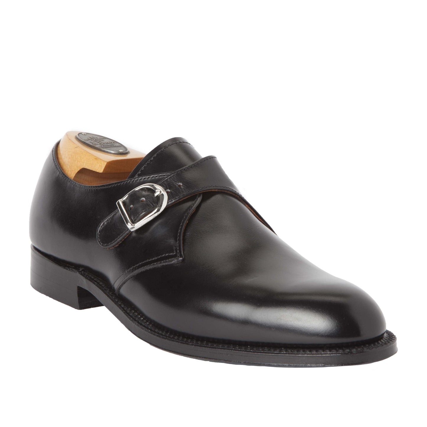 The Alden Madison 955 - Monk Strap in Black Calfskin is showcased on a white backdrop, featuring a shiny finish, single nickel buckle on the side, and wooden shoe tree inside, emphasizing its classic design.