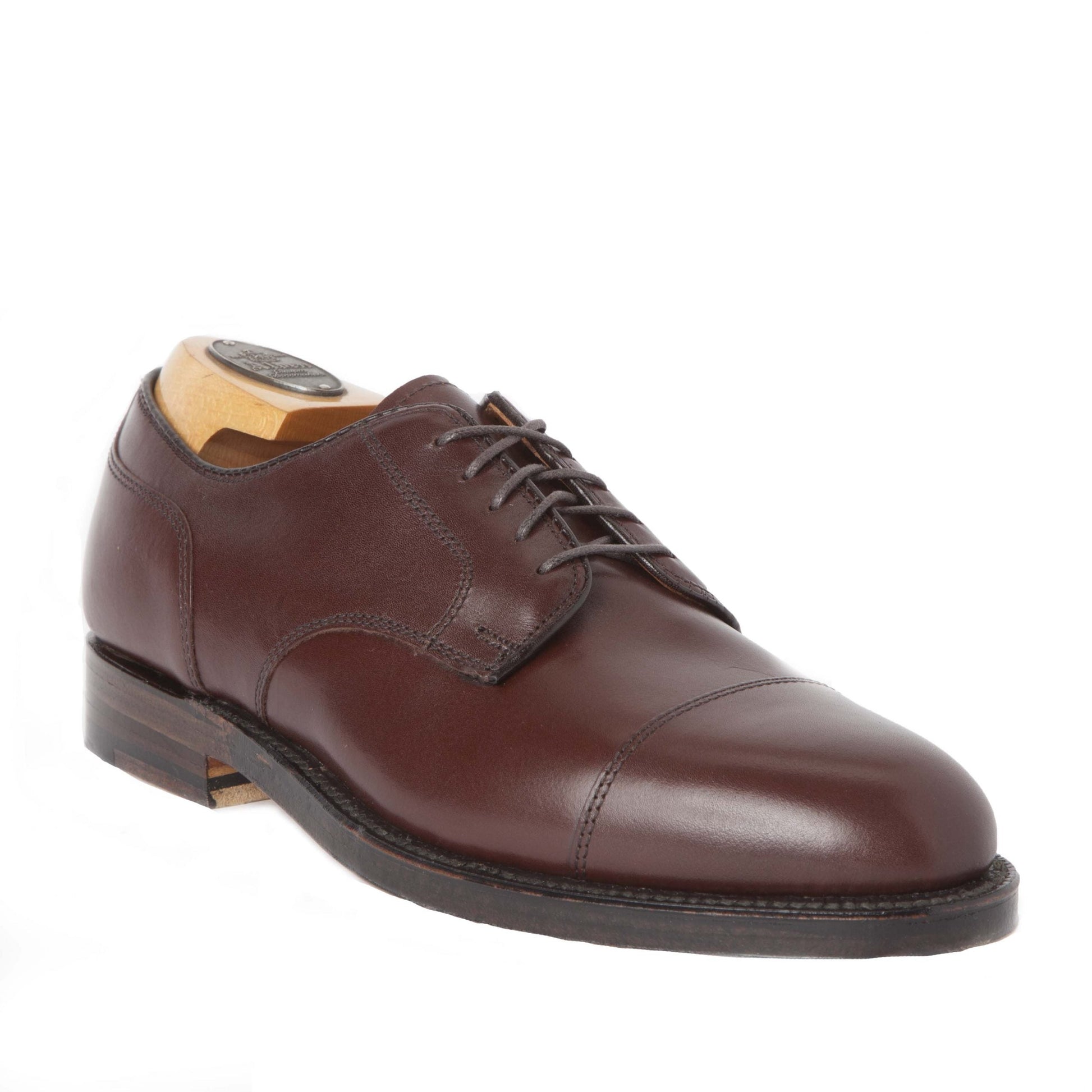 Alden Madisons 972 Cap Toe Blucher in Walnut Brown is a refined calfskin dress shoe with laces, crafted on the Aberdeen Last. It features a cap toe design and includes a wooden shoe tree, complemented by its dark leather sole for a polished classic look.