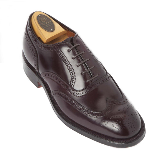 The Alden Madison 974 - Wing Tip Bal Color 8 Shell Cordovan is a polished dark brown dress shoe with brogue perforations and lace-up closure, crafted on the Tremont Last and shown with a wooden shoe tree inside.