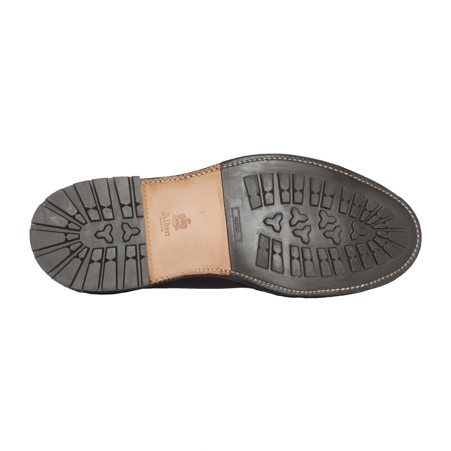 The image shows the sole of the Alden Madison 942C - 3 Eye Dutton in Brown Alpine Grain, featuring a black Commando Sole with a tan leather center embossed with the logo and brand name, patterned tread for grip, and detailed white stitching.