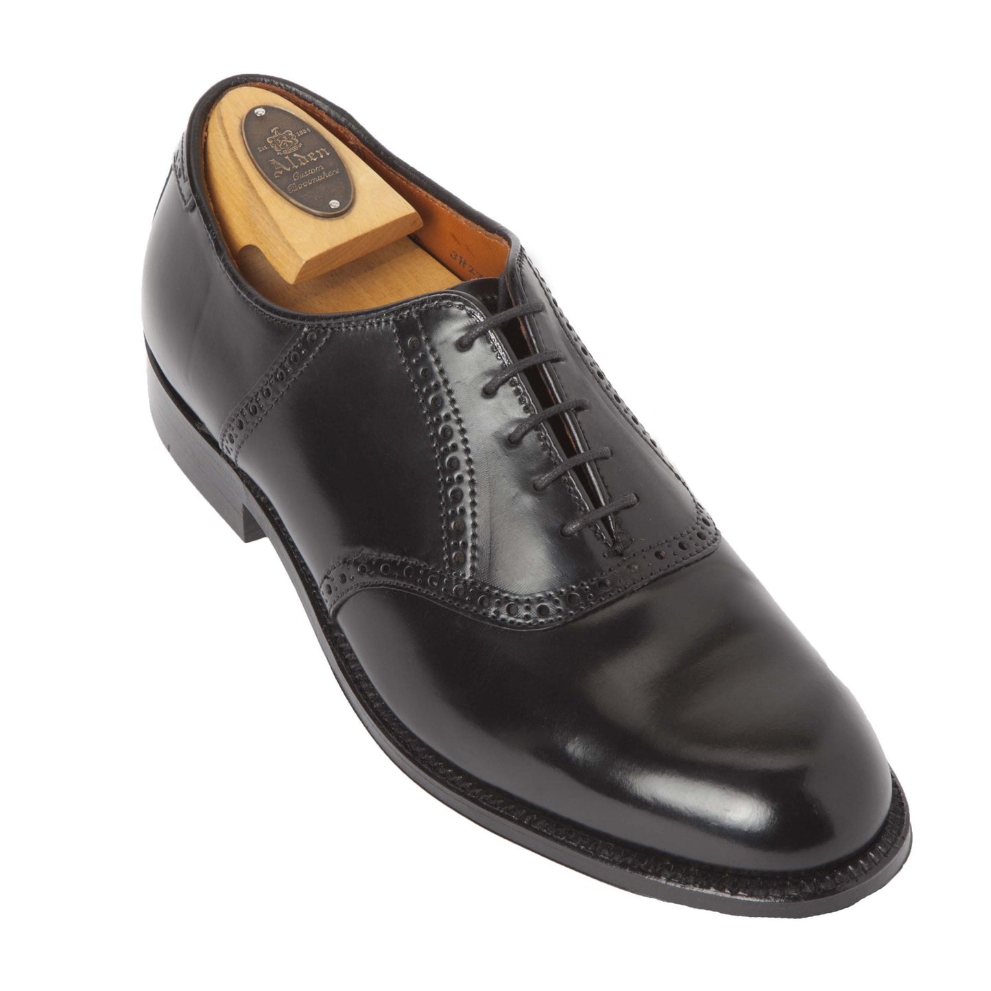 The Alden Madison 993 - Saddle Oxford Black Shell Cordovan is a shiny black oxford dress shoe with brogue detailing, laces, a wooden shoe tree, and leather outsole, shown angled left on a white background.