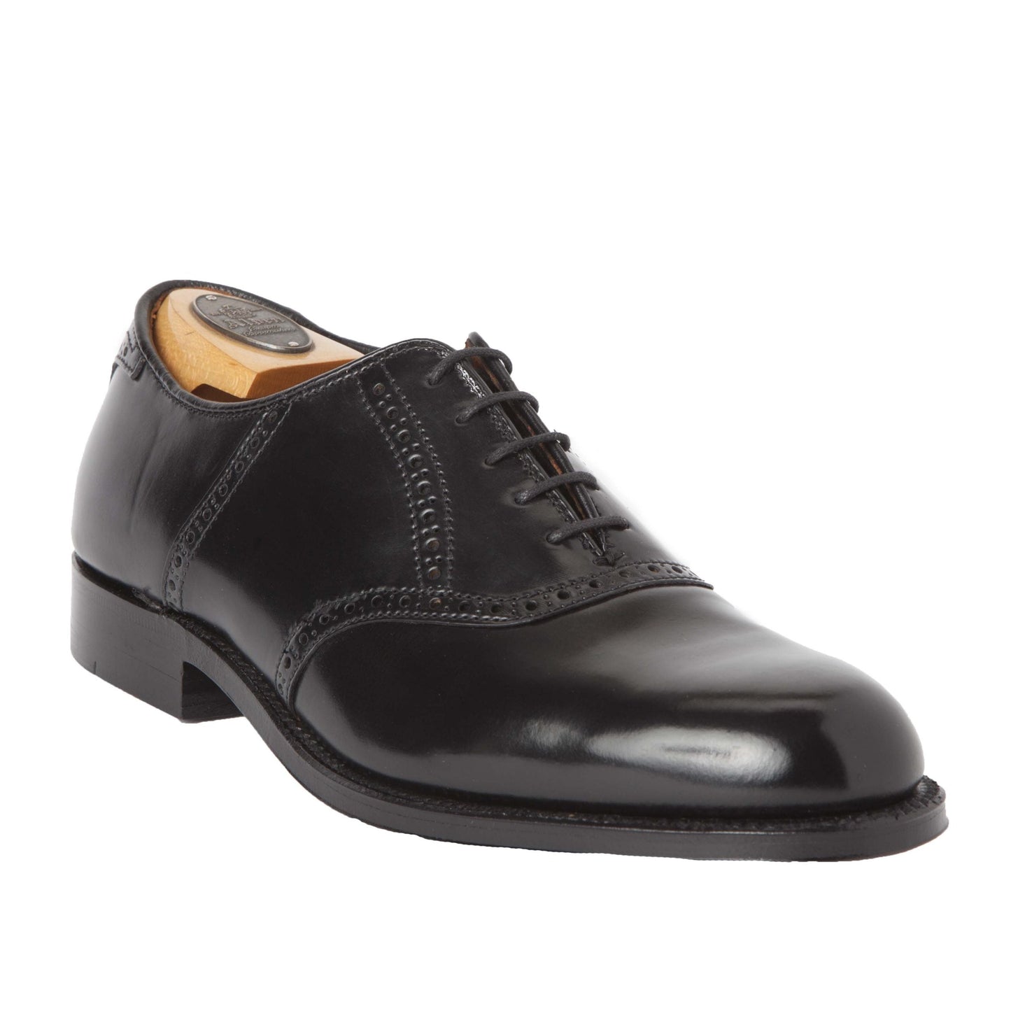 A single Alden Madison 993 - Saddle Oxford Black Shell Cordovan dress shoe, featuring black leather, brogue detailing, closed lacing, a leather outsole, and a wooden shoe tree inside.