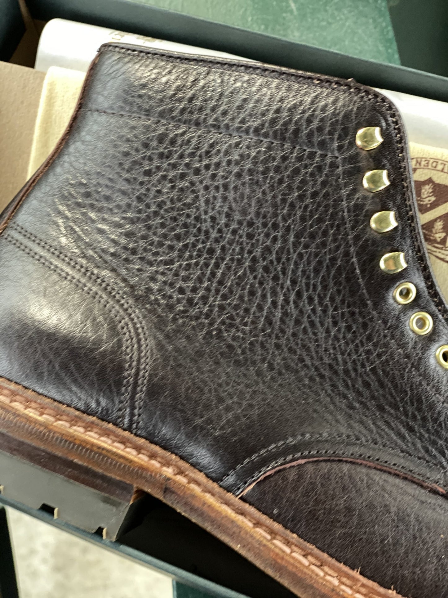 Close-up of the Alden Madison D1808HC - Stitchup 2/2 Boot in Arabica Lux7, featuring dark brown textured calfskin leather, metal eyelets, speed hooks, and a tan stitched sole, shown resting on its side.