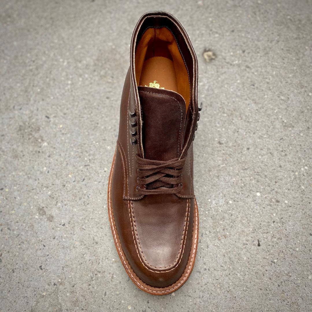 The Alden Madison 4012HC - Indy Boot in Brown Rusticalf features laces, visible stitching, and a light brown sole on a gray concrete surface, crafted on the Truebalance Last for comfort and style.