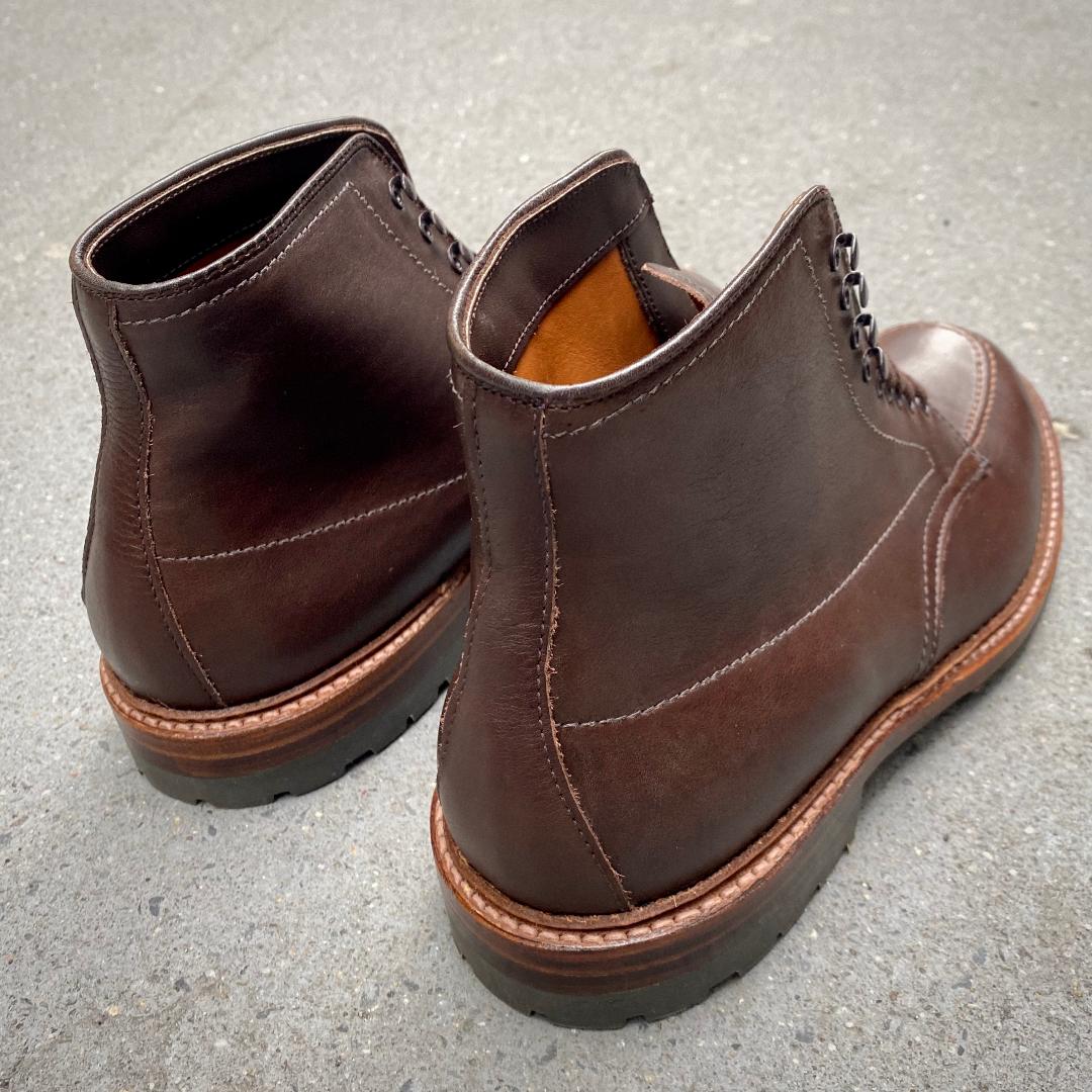 The Alden Madison 4012HC Indy Boot in Brown Rusticalf features visible stitching, thick 360 Commando soles, and a tan interior, shown on a gray textured surface.