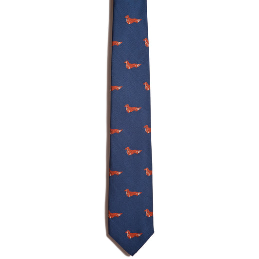 The Alden Madison Dachshund (longhair) necktie features a blue jacquard design with small, evenly spaced red dachshund silhouettes, shown on a white background.