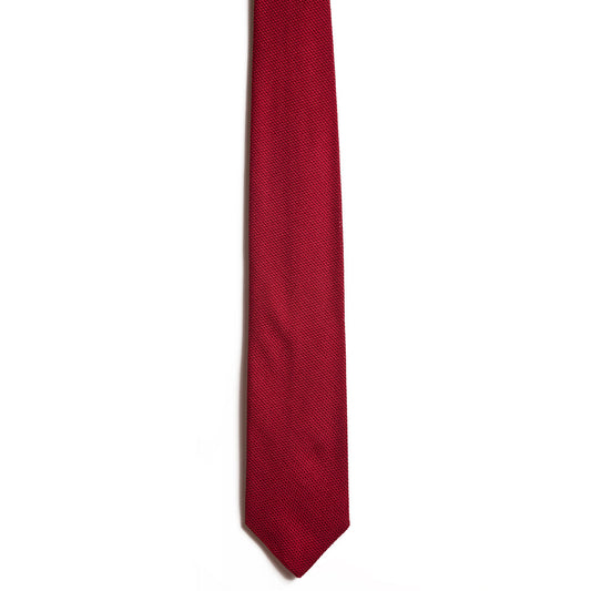 A close-up of a red Alden Madison tie, crafted from luxurious Italian silk, set against a plain white background. The New York City ateliers piece is neatly arranged, highlighting its sleek classic design with subtle texture.